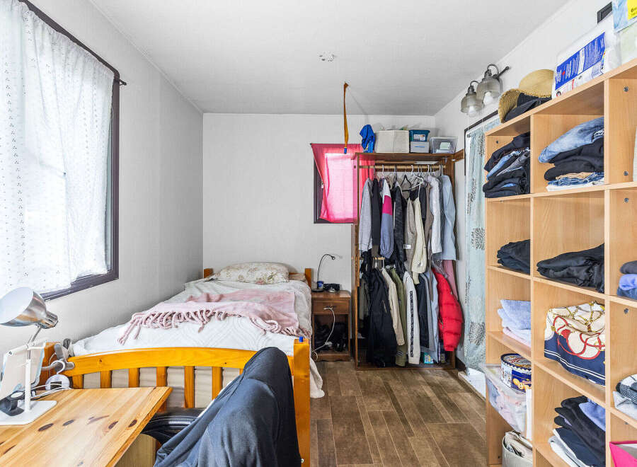 Discover a cozy and organized living space featuring a comfortable bed with a soft pink throw, perfect for relaxation.