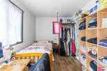 Discover a cozy and organized living space featuring a comfortable bed with a soft pink throw, perfect for relaxation.