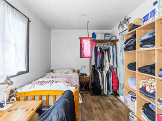Discover a cozy and organized living space featuring a comfortable bed with a soft pink throw, perfect for relaxation.