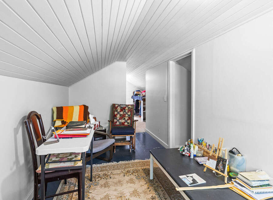 Discover a versatile space perfect for a home office or craft room, featuring a comfortable seating area with a colorful blanket and a dedicated workspace.
