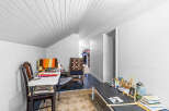 Discover a versatile space perfect for a home office or craft room, featuring a comfortable seating area with a colorful blanket and a dedicated workspace.