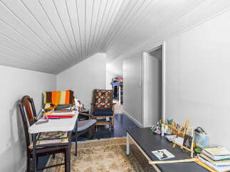 Discover a versatile space perfect for a home office or craft room, featuring a comfortable seating area with a colorful blanket and a dedicated workspace.