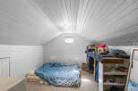 Discover this charming attic bedroom, featuring a cozy bed with blue patterned bedding and a unique hexagonal window that floods the space with natural light.