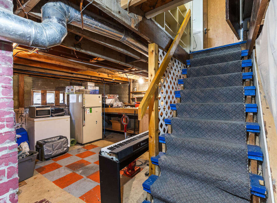 Discover the potential of this unfinished basement, featuring a sturdy staircase with carpeted treads and blue risers, leading to a versatile space ready for your personal touch.
