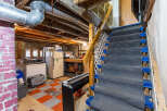 Discover the potential of this unfinished basement, featuring a sturdy staircase with carpeted treads and blue risers, leading to a versatile space ready for your personal touch.