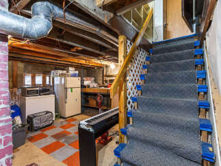 Discover the potential of this unfinished basement, featuring a sturdy staircase with carpeted treads and blue risers, leading to a versatile space ready for your personal touch.