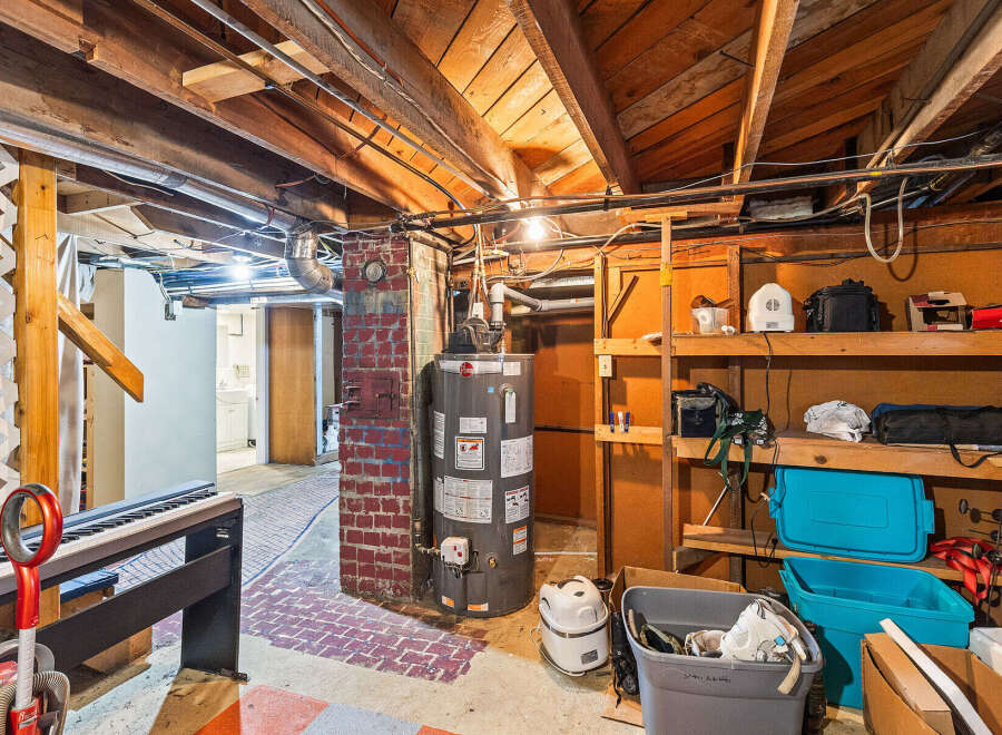 Explore the potential of this unfinished basement, featuring a functional water heater and ample storage shelves perfect for organizing your belongings.