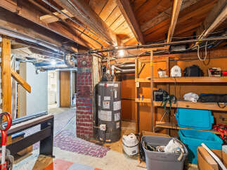 Explore the potential of this unfinished basement, featuring a functional water heater and ample storage shelves perfect for organizing your belongings.