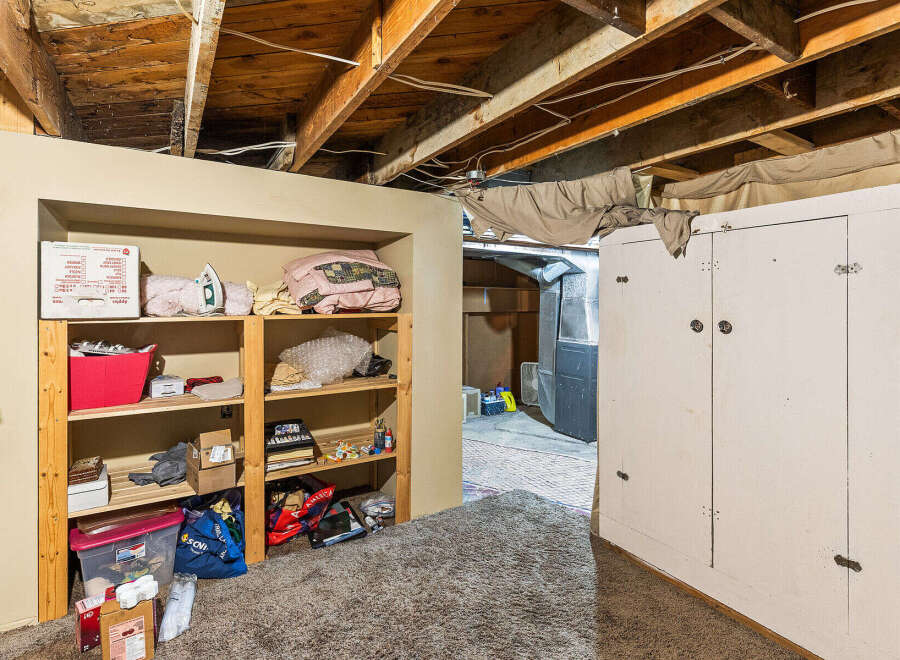 Discover ample storage solutions in this basement featuring a tall, white cabinet and open shelving units.