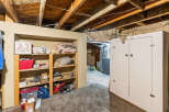 Discover ample storage solutions in this basement featuring a tall, white cabinet and open shelving units.
