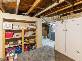 Discover ample storage solutions in this basement featuring a tall, white cabinet and open shelving units.