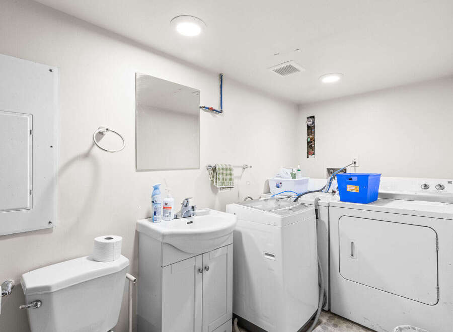 This functional laundry room features a toilet, sink, and a stacked washer and dryer, making chores a breeze.