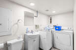 This functional laundry room features a toilet, sink, and a stacked washer and dryer, making chores a breeze.