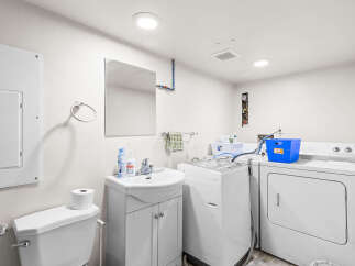 This functional laundry room features a toilet, sink, and a stacked washer and dryer, making chores a breeze.