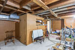 Explore the potential of this unfinished basement, featuring exposed wooden beams and ample space for customization.