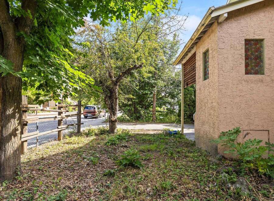 Discover this charming property featuring a rustic wooden fence and lush greenery, perfect for outdoor enjoyment.