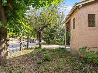 Discover this charming property featuring a rustic wooden fence and lush greenery, perfect for outdoor enjoyment.