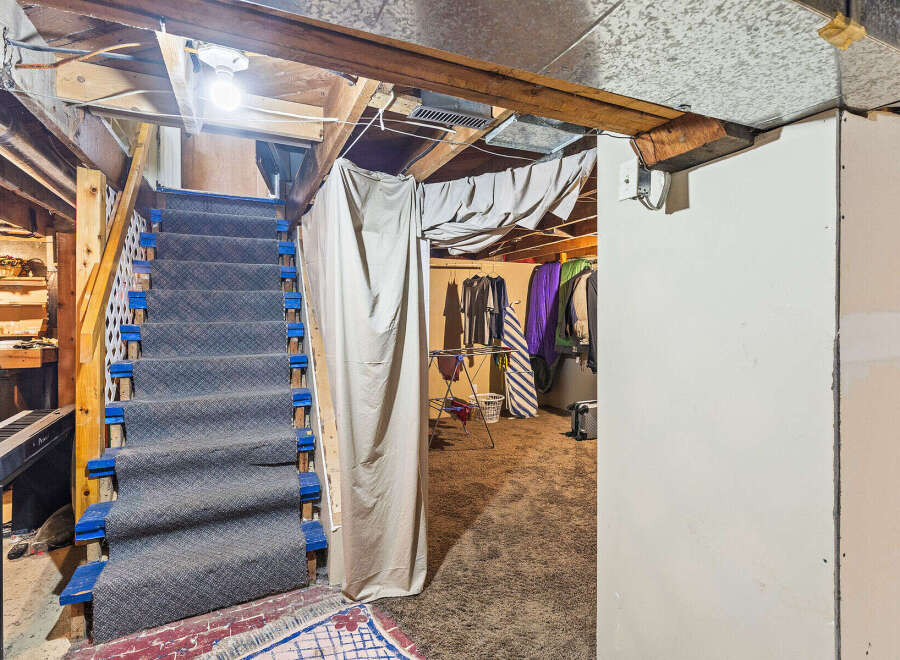 Discover the potential of this unfinished basement, featuring a carpeted staircase leading to a versatile space.
