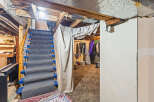 Discover the potential of this unfinished basement, featuring a carpeted staircase leading to a versatile space.