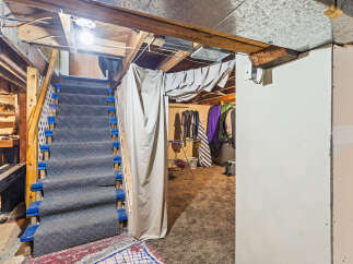 Discover the potential of this unfinished basement, featuring a carpeted staircase leading to a versatile space.