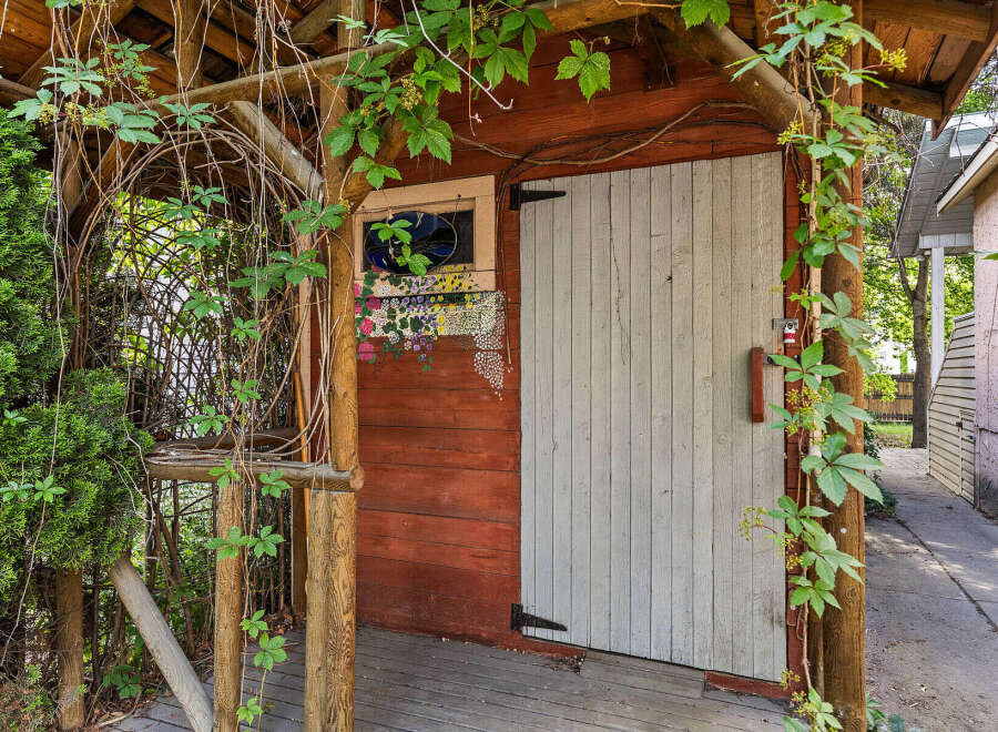 Charming rustic shed with a weathered wood exterior, featuring a decorative stained-glass window and vibrant floral accents.