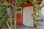 Charming rustic shed with a weathered wood exterior, featuring a decorative stained-glass window and vibrant floral accents.