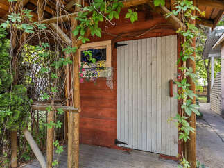 Charming rustic shed with a weathered wood exterior, featuring a decorative stained-glass window and vibrant floral accents.