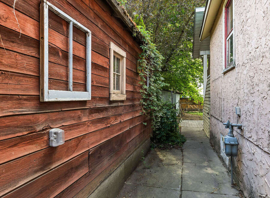 Explore the charming exterior of this property, featuring a rustic wooden shed with two windows and a smaller, functional window.