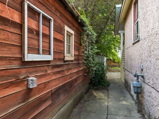 Explore the charming exterior of this property, featuring a rustic wooden shed with two windows and a smaller, functional window.