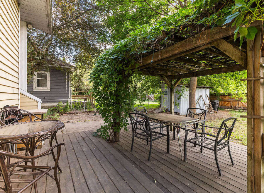 Enjoy outdoor living on this charming wooden deck, complete with a covered pergola draped in lush greenery.