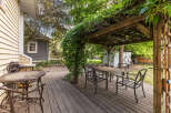 Enjoy outdoor living on this charming wooden deck, complete with a covered pergola draped in lush greenery.