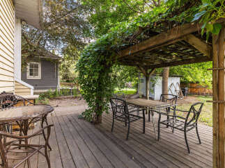 Enjoy outdoor living on this charming wooden deck, complete with a covered pergola draped in lush greenery.