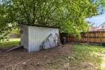 Discover the potential of this backyard space, featuring a versatile metal shed perfect for storage or a workshop.