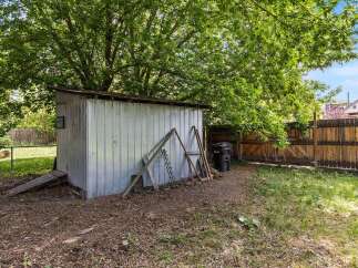Discover the potential of this backyard space, featuring a versatile metal shed perfect for storage or a workshop.