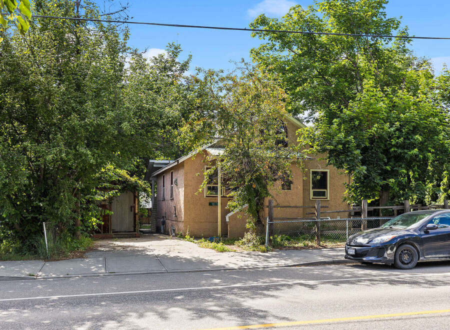 Discover this charming property featuring a stucco exterior and a metal roof, nestled amongst mature trees for privacy and shade.
