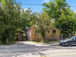 Discover this charming property featuring a stucco exterior and a metal roof, nestled amongst mature trees for privacy and shade.