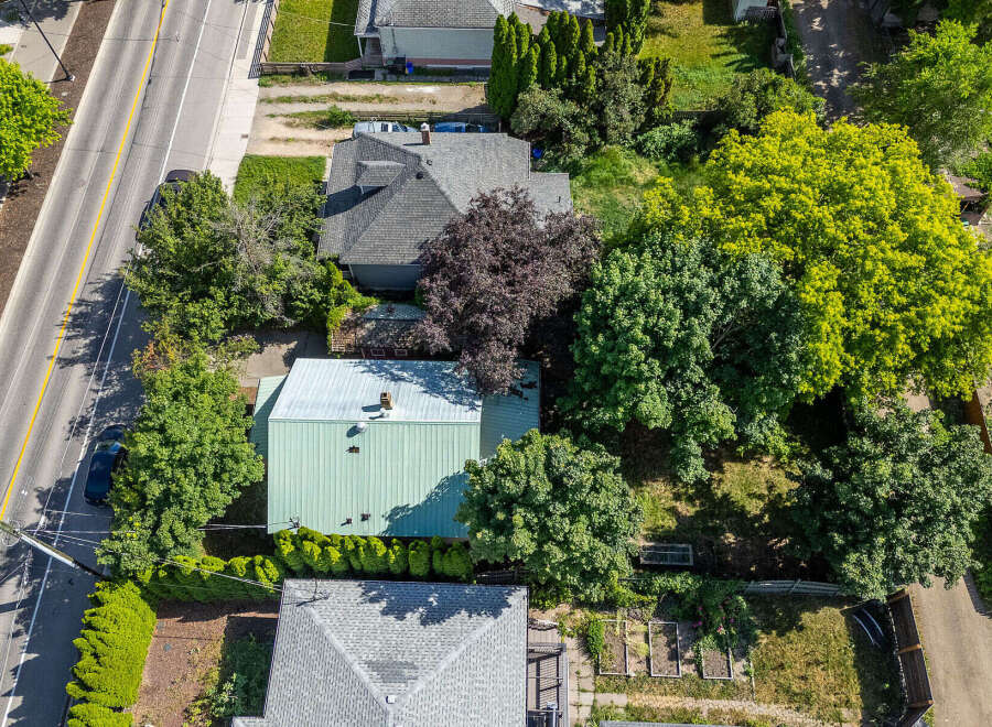 Discover this charming property featuring a well-maintained home with a distinctive green metal roof, nestled amidst lush greenery and mature trees.