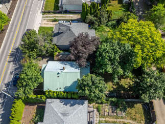 Discover this charming property featuring a well-maintained home with a distinctive green metal roof, nestled amidst lush greenery and mature trees.