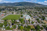 Discover this expansive aerial view of a vibrant suburban neighborhood, showcasing a well-maintained soccer field adjacent to a modern school complex.