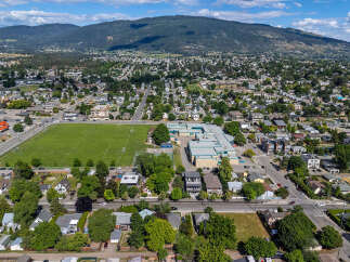 Discover this expansive aerial view of a vibrant suburban neighborhood, showcasing a well-maintained soccer field adjacent to a modern school complex.
