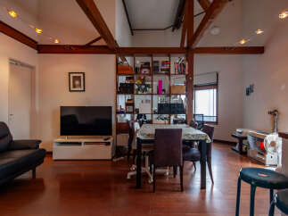 Experience modern living in this spacious open-concept apartment, featuring a sleek black leather sofa and a large flat-screen TV perfect for entertainment.