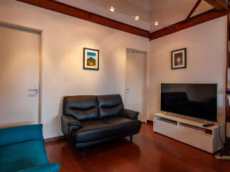 Experience modern living in this stylish living room featuring a sleek black leather sofa and a vibrant teal accent chair.