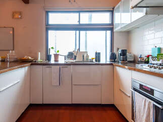 This modern kitchen features sleek white cabinetry and a warm wooden countertop, creating a bright and inviting space.