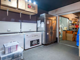This commercial kitchen space features multiple chest freezers and a large stainless steel refrigerator, ideal for food storage and preparation.