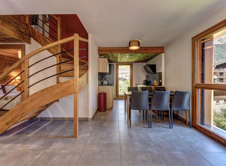 Experience modern alpine living in this beautifully appointed apartment, featuring a stunning wooden spiral staircase leading to the upper levels.