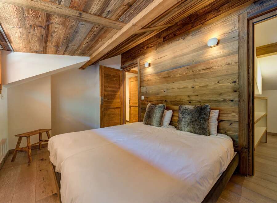 Experience rustic charm in this cozy bedroom featuring a beautifully paneled wooden ceiling and walls, creating a warm and inviting atmosphere.