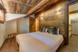 Experience rustic charm in this cozy bedroom featuring a beautifully paneled wooden ceiling and walls, creating a warm and inviting atmosphere.