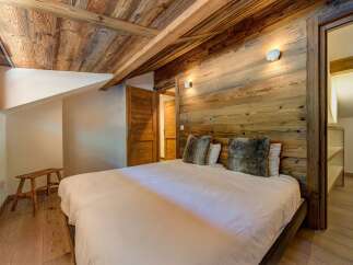 Experience rustic charm in this cozy bedroom featuring a beautifully paneled wooden ceiling and walls, creating a warm and inviting atmosphere.