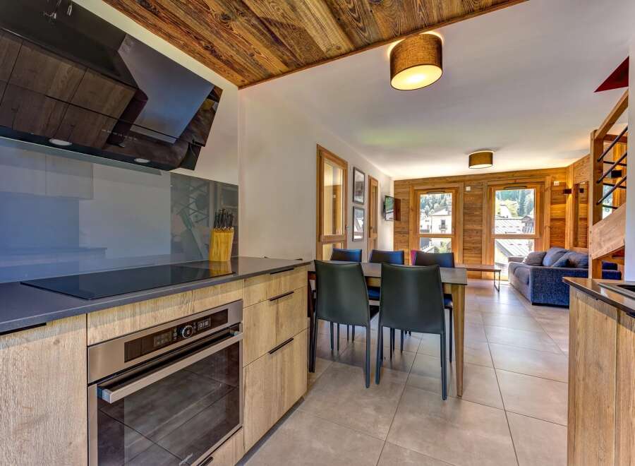 Experience modern alpine living in this beautifully appointed apartment, featuring a sleek kitchen with a built-in oven and induction hob, complemented by warm wooden cabinetry.