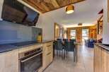 Experience modern alpine living in this beautifully appointed apartment, featuring a sleek kitchen with a built-in oven and induction hob, complemented by warm wooden cabinetry.